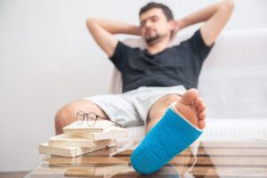 Close up man's broken leg in blue splint for treatment of injuries from ankle sprain at home.