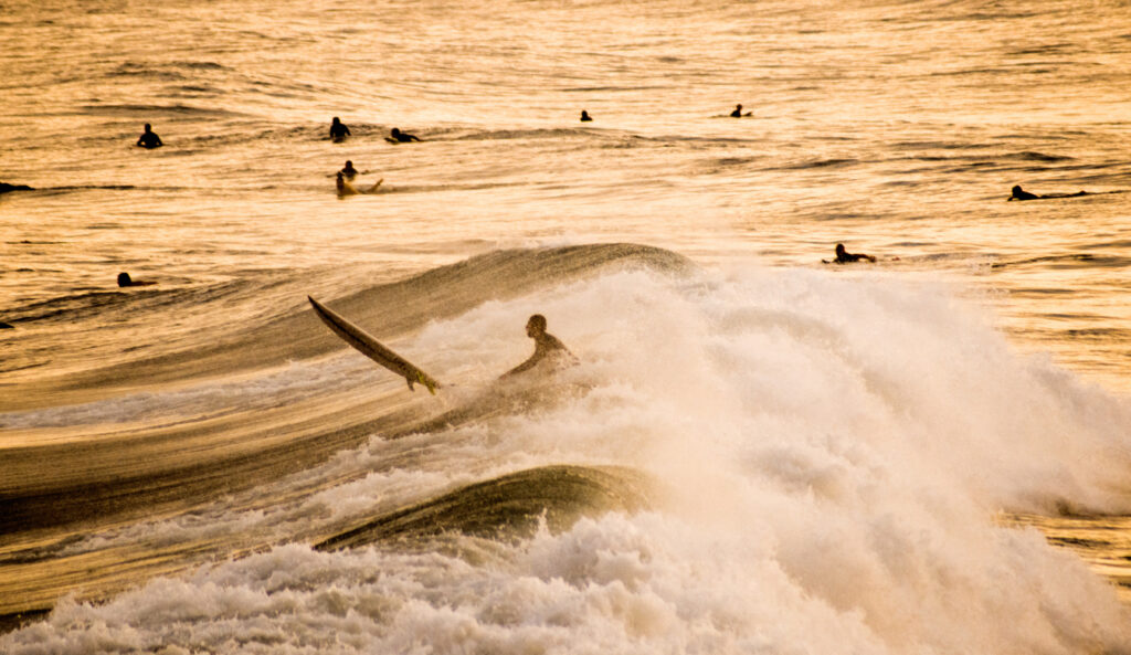 Silhouette of a Surfer getting past breaking wave