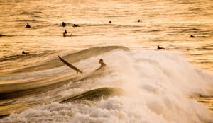 Silhouette of a Surfer getting past breaking wave